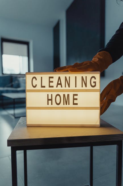 A light blue dustpan and a wooden-handled broom with natural bristles are hanging on a white wall, showcasing a clean and organized area of a residential or commercial space. The dustpan is empty and 